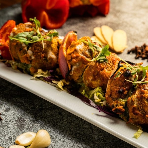 Stuffed bell peppers and red peppers on a white platter, garnished with fresh herbs.