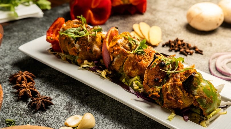 Stuffed bell peppers and red peppers on a white platter, garnished with fresh herbs.