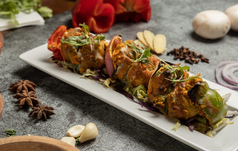 Stuffed bell peppers and red onions on a white platter, garnished with cilantro.